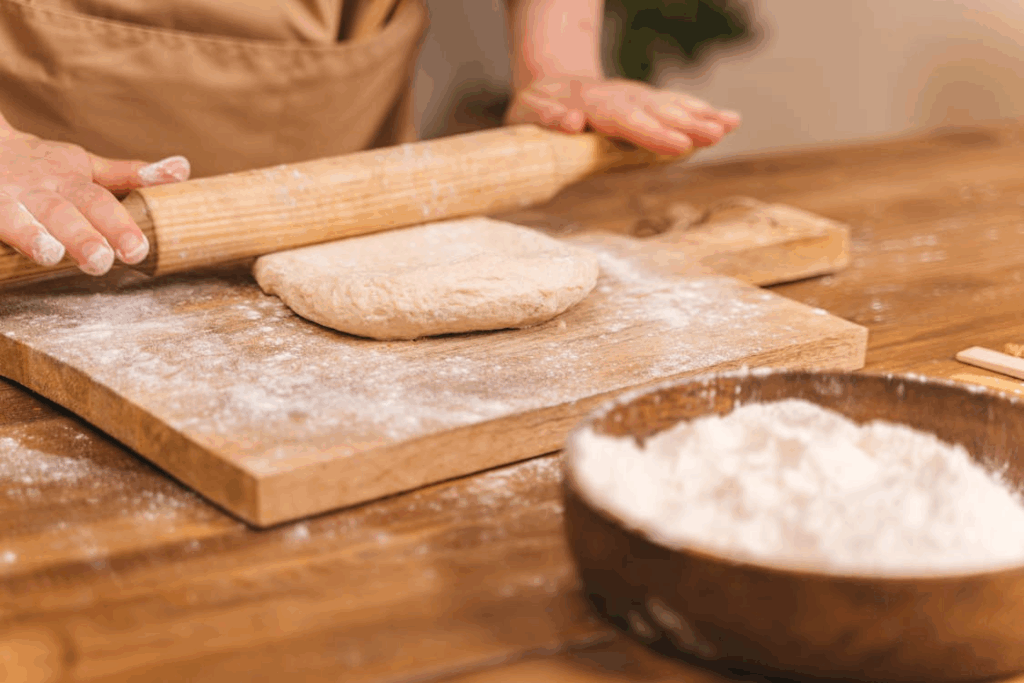 Person shaping dough with a rolling pin while making a simple homemade bread recipe.