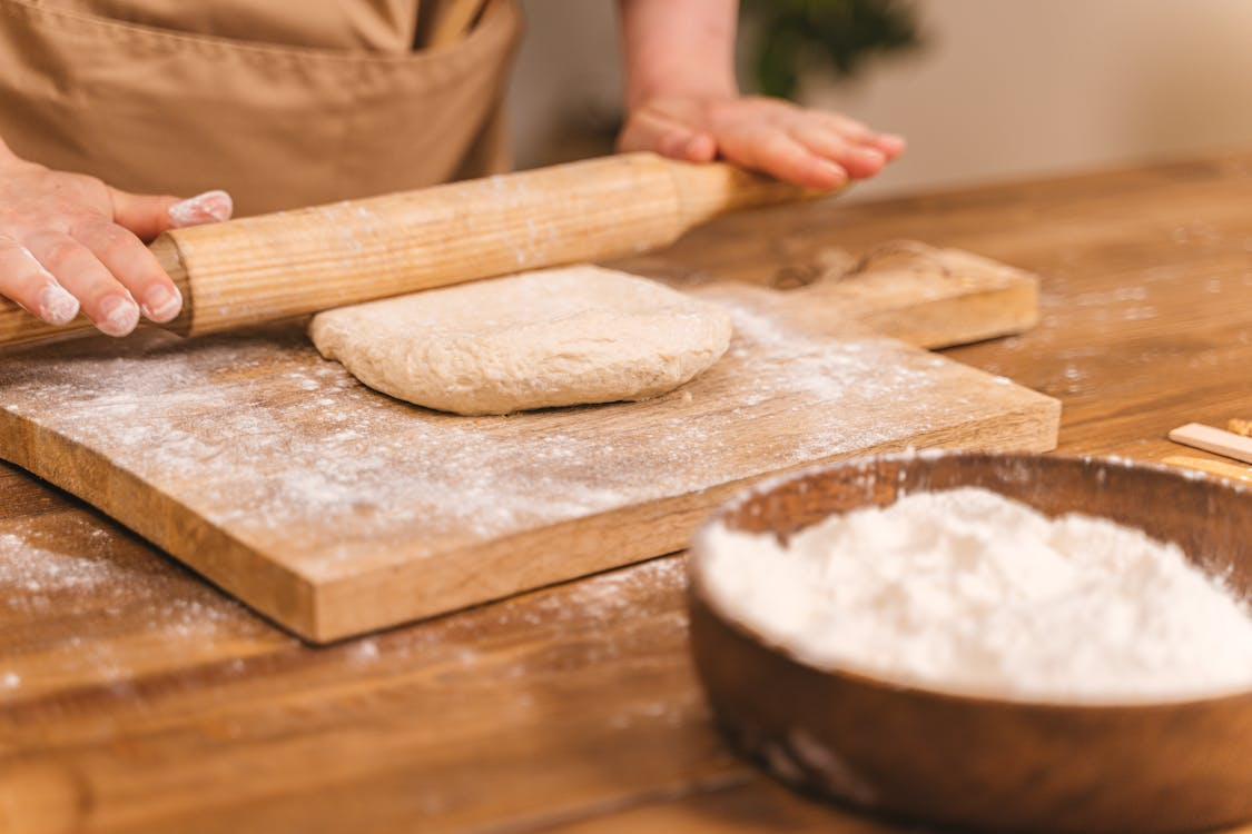 Person shaping dough with a rolling pin while making a simple homemade bread recipe.