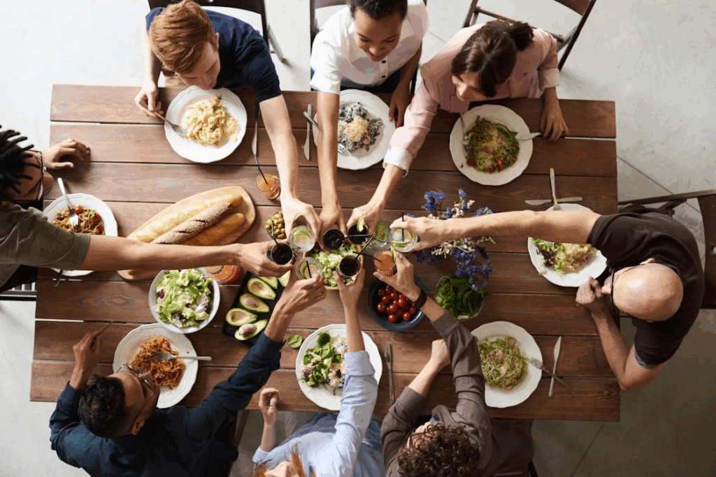 Overhead view of friends enjoying a stress-free dinner party, raising glasses together.