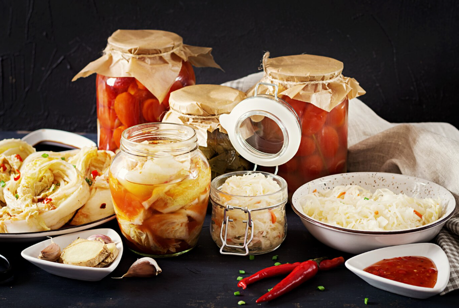 Assorted fermented vegetables in jars and bowls, including sauerkraut and kimchi, highlighting gut-friendly probiotics