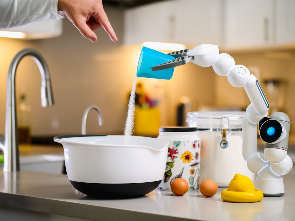 Robotic arm in a modern kitchen pouring sugar from a measuring cup, illustrating future of food technology.