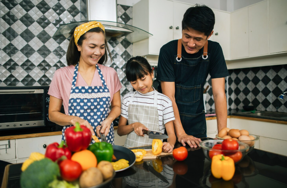 Smiling parents and child cooking together in a home kitchen.